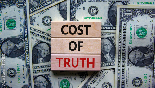 Concept text 'cost of truth' on wooden blocks on a beautiful background from dollar bills.