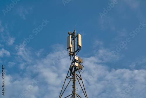 Telecommunications tower with transmitters. Base station with transmitting antennas on a telecommunications tower against the blue sky.