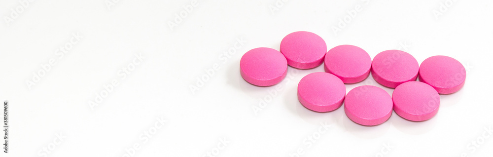 Close-up of pink round tablets on a white background, banner Close-up of pink round tablets on a white background, banner
