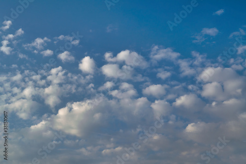White cumulus clouds against a bright blue summer sky. © Anatoliy