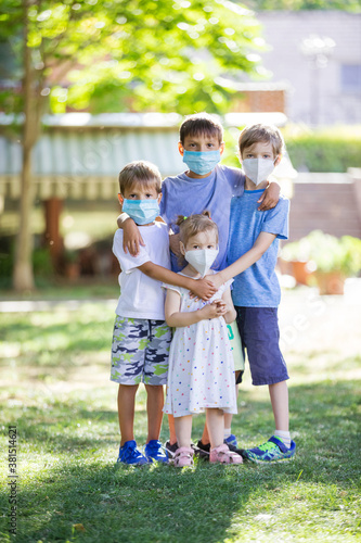 Young children in protective masks on faces outdoors. Quarantine.
