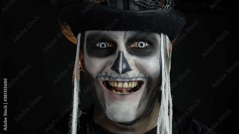 Close-up shot of creepy man in skeleton Halloween makeup opening eyes and looking spooky at camera Close-up shot of creepy man in skeleton Halloween makeup opening eyes and looking spooky at camera