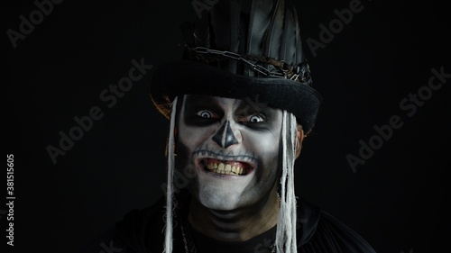 Creepy man with skeleton makeup in top-hat. Guy making faces, toothy smile. Halloween thematic party © Andrii Iemelianenko