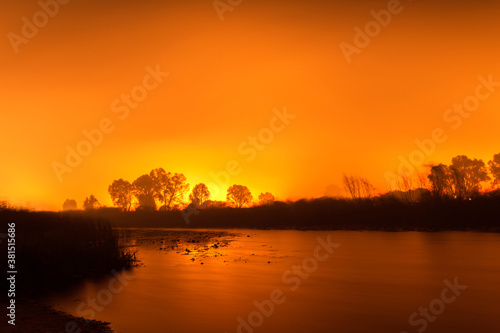 Peaceful river against the background of a fiery sky of forest fires