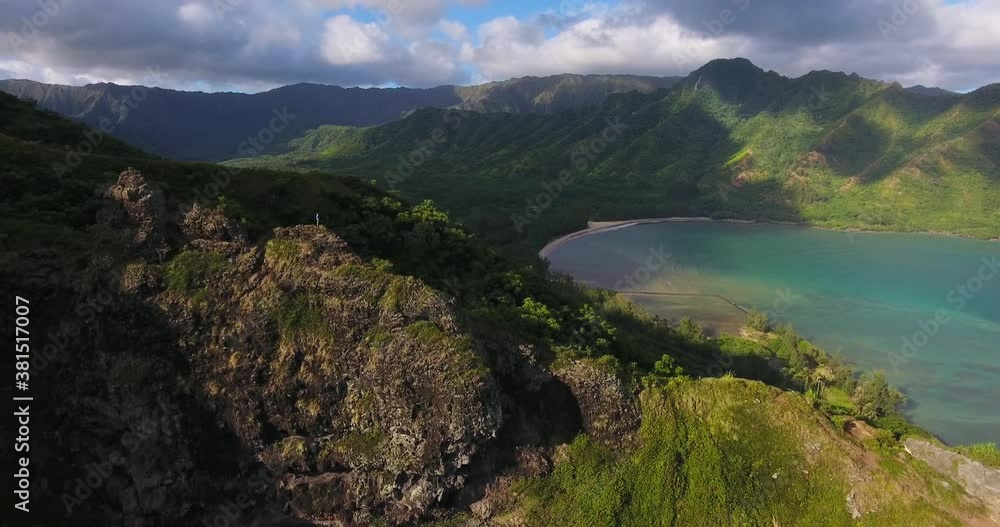 Woman hikes with view of Hawaiian coastline, wide aerial Woman hikes with view of Hawaiian coastline, wide aerial