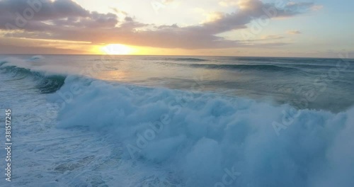 Wide aerial, sunset over ocean waves in Hawaii