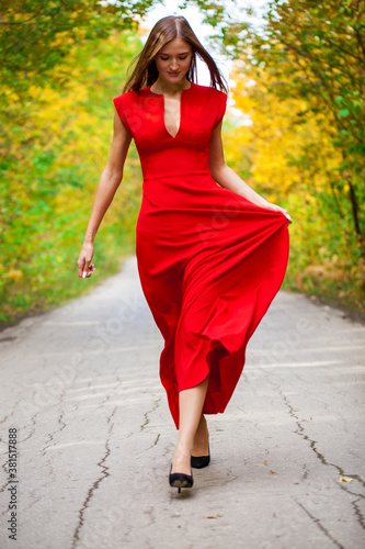 Young woman in red tight dress posing in autumn forest