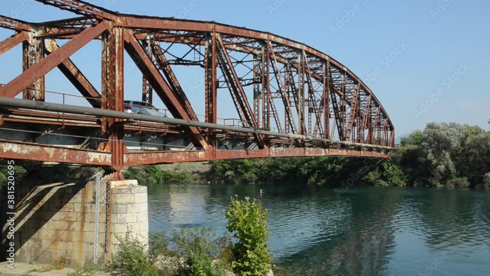 Old rusty bridge over the river. Transportation. Old metal bridge in nature. Border crossing. Steel bridge across the river against blue sky.
Old rusty bridge over the river. Transportation. Old metal bridge in nature. Border crossing. Steel bridge across the river against blue sky.