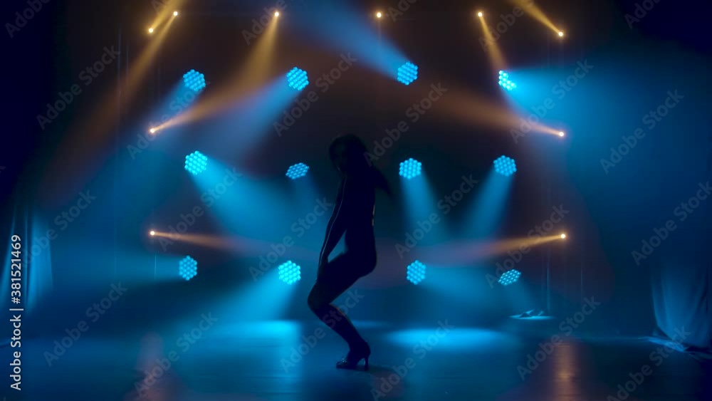 Hot sexy woman dancing in the studio against the background of flashing colored neon lights. A female dancer is silhouetted in revealing black lingerie. Slow motion. Hot sexy woman dancing in the studio against the background of flashing colored neon lights. A female dancer is silhouetted in revealing black lingerie. Slow motion.