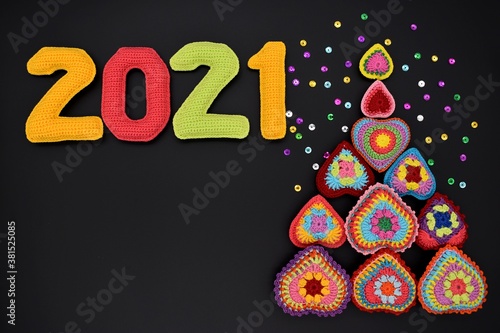 2021 New year, Christmas. Knitted colored numbers and a Christmas tree on a black background. Design, decor, amigurumi, creative.