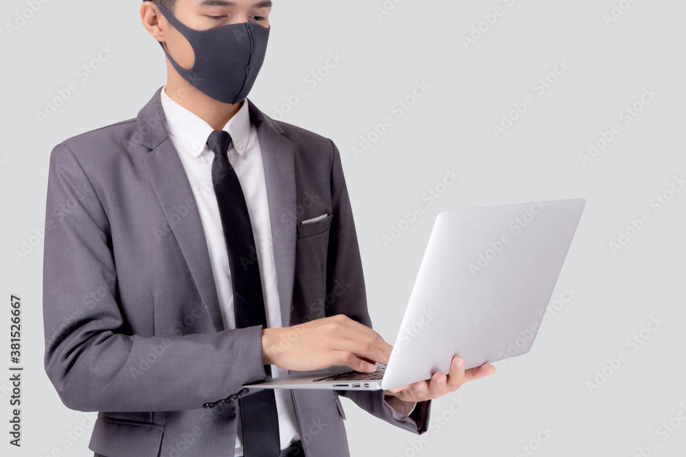 Young asian business man in face mask using laptop computer isolated on white background, quarantine and epidemic covid-19, businessman work from home for health, social distancing, new normal.