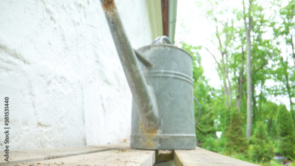 An old watering can on top of the wooden plank An old watering can on top of the wooden plank