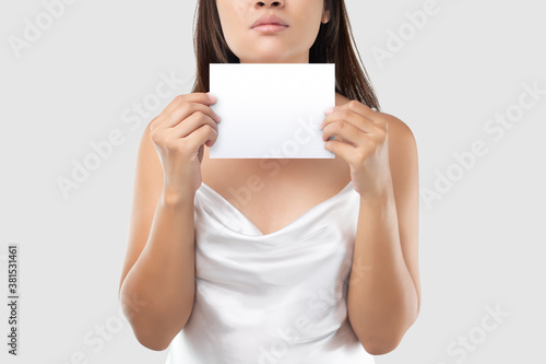 A Woman in white satin dress holding a white blank paper against a light gray background. © eddows
