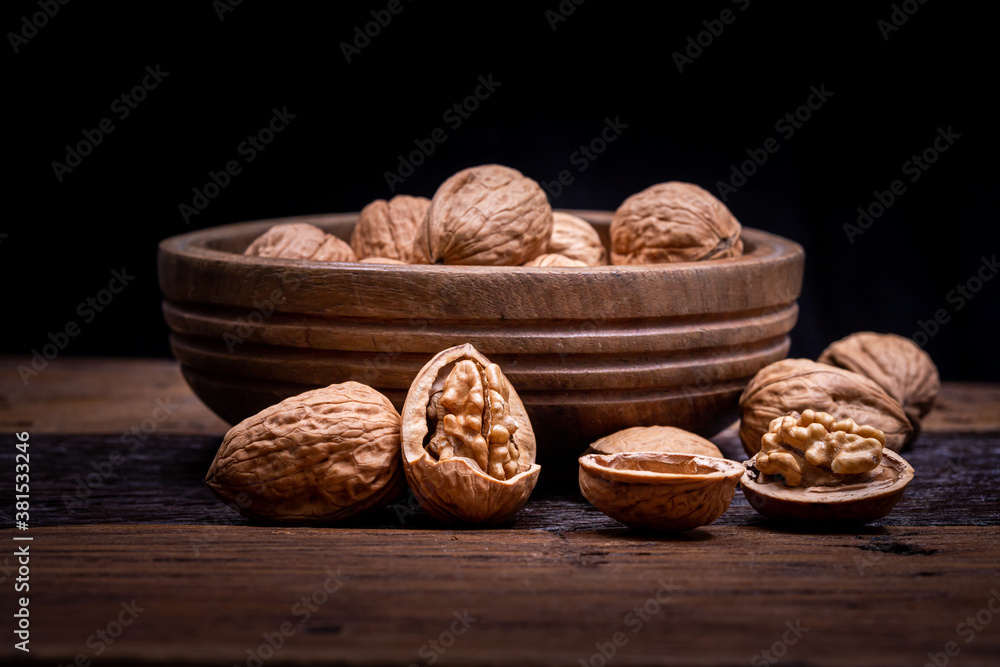 still life with Walnut kernels and whole walnuts on rustic old wooden table.