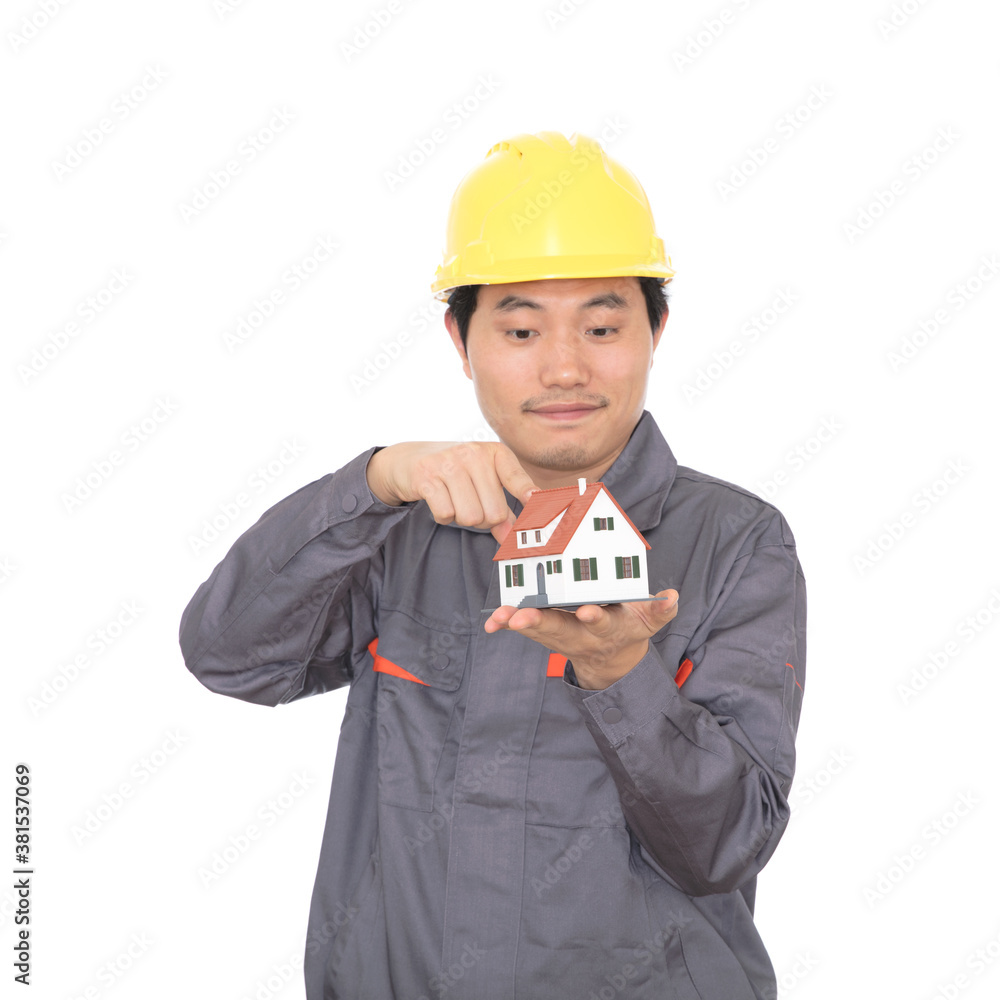 Migrant worker wearing yellow hard hat holding small house model in hand Migrant worker wearing yellow hard hat holding small house model in hand
