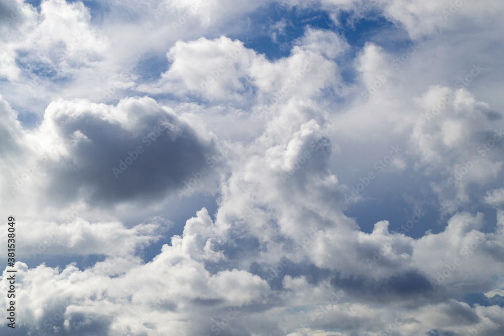 The blue sky shines through the clouds. Beautiful white cumulus clouds in the blue sky The blue sky shines through the clouds. Beautiful white cumulus clouds in the blue sky