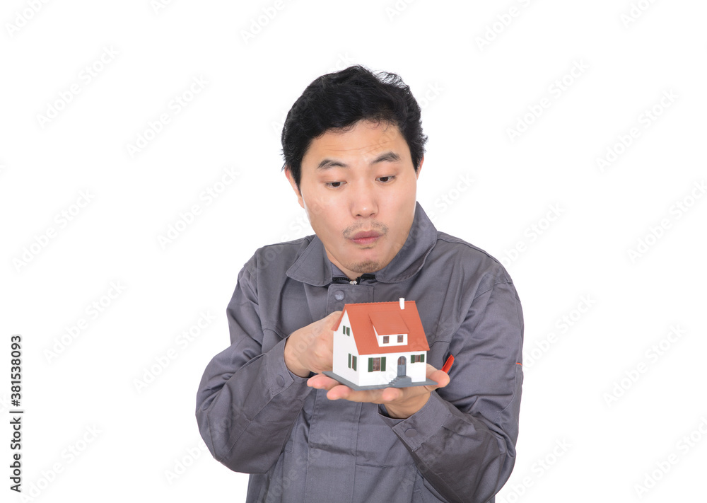 Construction worker in front of white background surprised with finger pointing at house model in other hand Construction worker in front of white background surprised with finger pointing at house model in other hand
