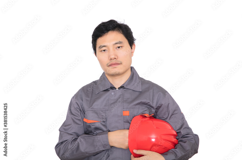 Confident young worker holding red hard hat in hand and standing in front of white background Confident young worker holding red hard hat in hand and standing in front of white background