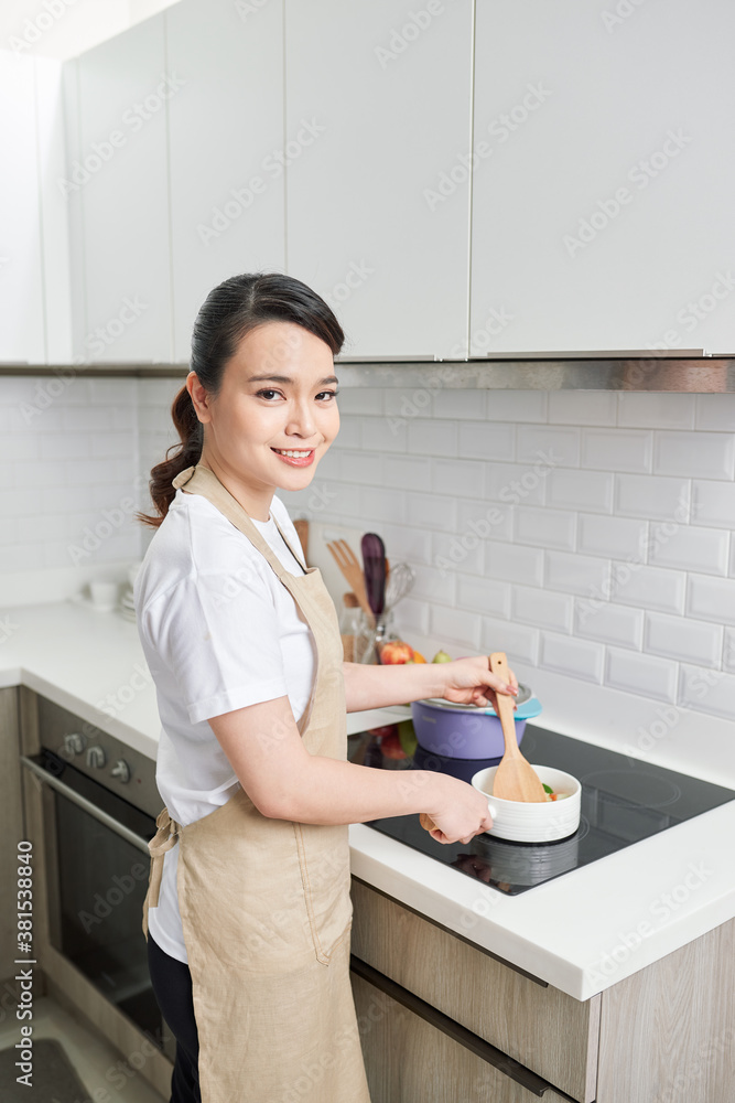 young attractive asian woman cooks in a kitchen,saute young attractive asian woman cooks in a kitchen,saute