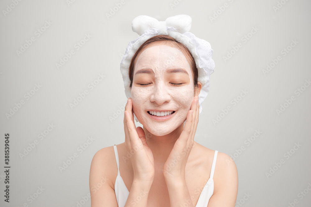 Cheerful young Asian woman with facial clay mask isolated on white background. Cheerful young Asian woman with facial clay mask isolated on white background.