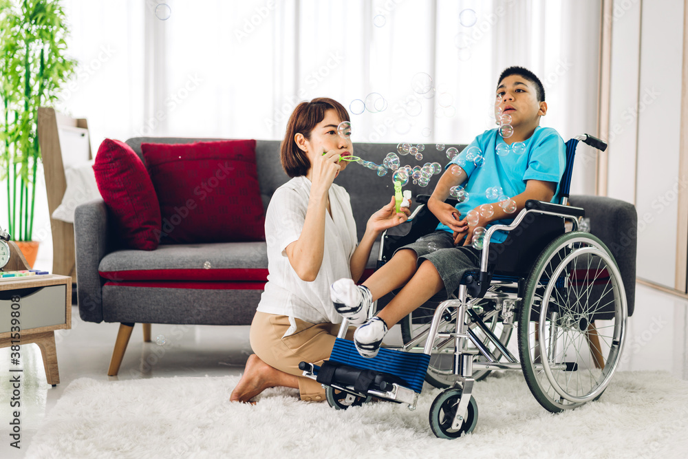 Portrait of enjoy happy love family asian mother playing and carer helping look at disabled son child sitting in wheelchair moments good time at home.disability care concept Portrait of enjoy happy love family asian mother playing and carer helping look at disabled son child sitting in wheelchair moments good time at home.disability care concept