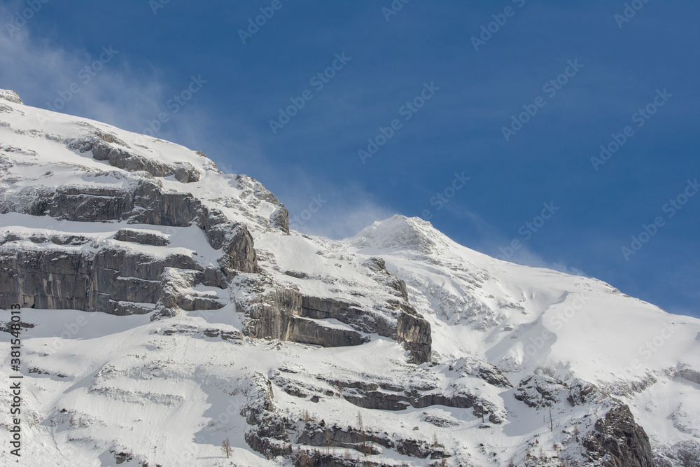 Bergmassiv im Schnee mit Verwehungen und blauer Himmel