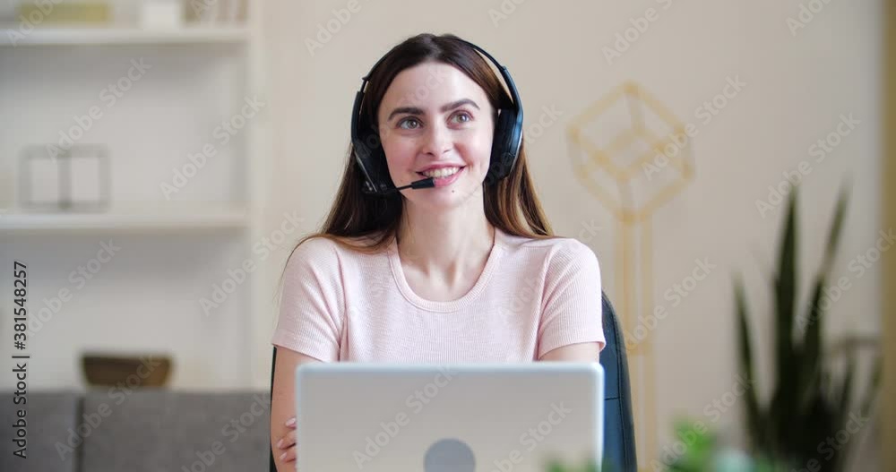Head shot portrait young millennial woman sit at home table wear headset talks, consulting customers, distant communication. Conversation with clients by call line, help service, modern tech concept