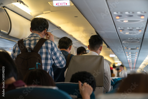 Obraz na plátně People are standing in an airplane cabin before disembarking