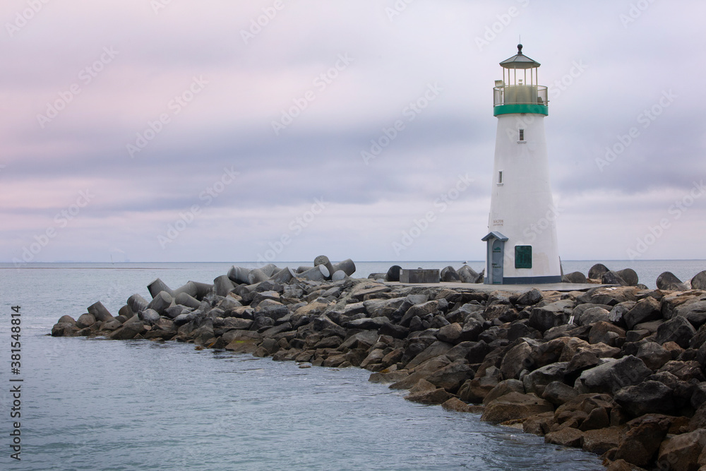 Lighthouse on rock Jetty in the ocean at dusk with light on