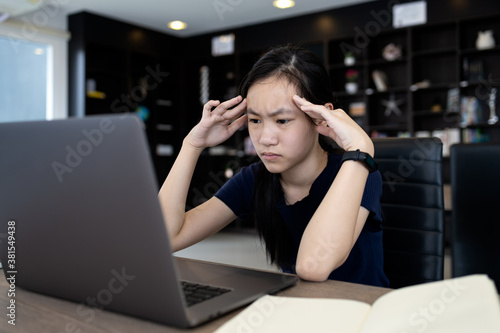 Tired asian student working at desk,use laptop computer for a long time on job,touching head with her hands,girl having a headache,dizziness and stress,overwork or computer vision syndrome concept