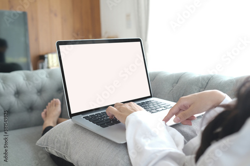 Close up young woman using laptop on sofa after waking up at weekend morning.
