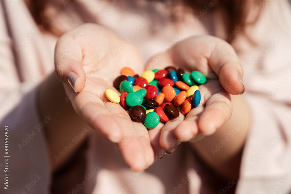 Colourful Chocolate candies in dessert lover hands.