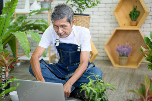 happy senior asian retired man with laptop is relaxing and enjoying leisure activity in garden at home.