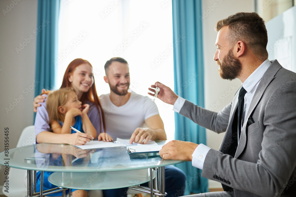 Obraz premium young caucasian family getting keys from their house by real estate agent, male in suit give them keys, happy family with child girl sit smiling
