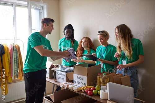 diverse volunteers packing, collecting humanitarian aid in donation box. multi-ethnic group of people working in charitable foundation helping in crises and homeless