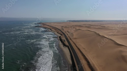 Aerial drone view of Namibian Atlantic coastline, road along the coast from Swakopmund to Walvis Bay, beach, surf break point, landscape with ocean background of sand dunes at Namibia's west coast