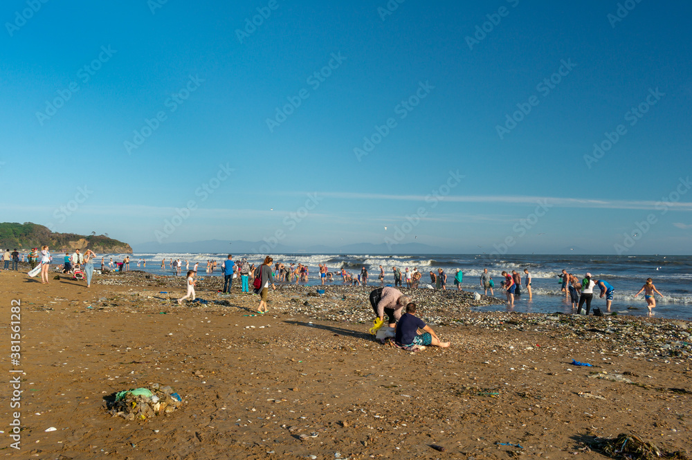 People on a dirty sea beach. A lot of garbage on the sea beach