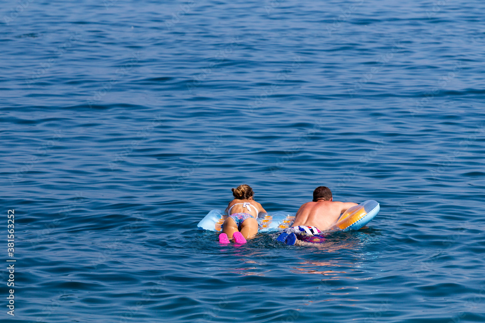 man and a woman on an air mattress floating on the sea