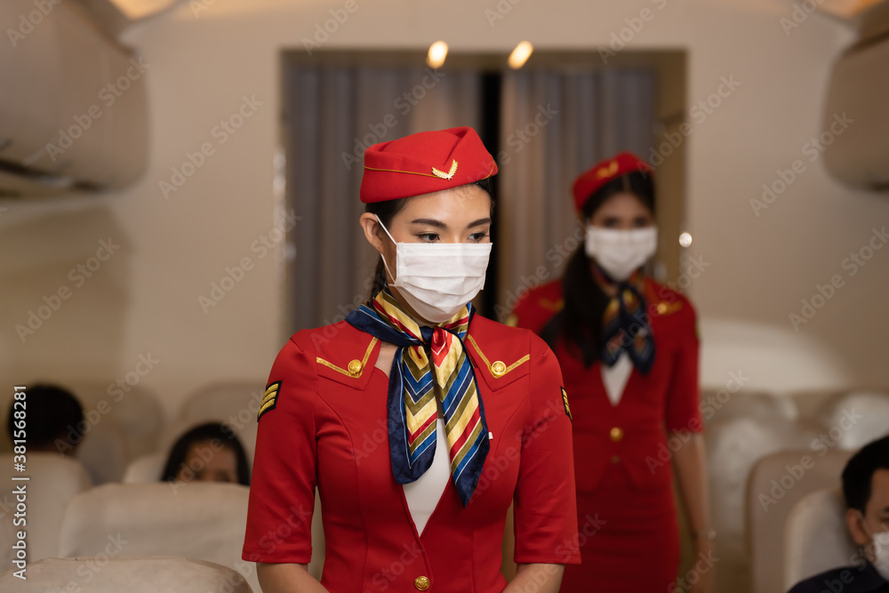 female asian crew serviced on flight, Airline passengers wear protective masks, after the virus crisis people travel but still protect themselves by wearing masks.