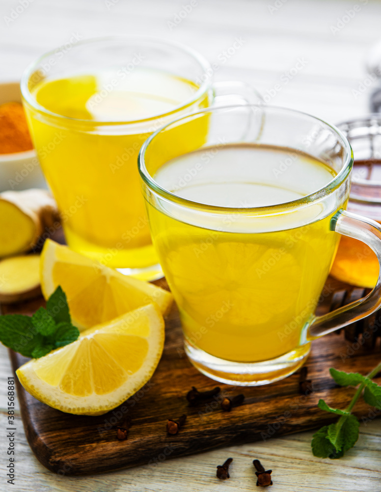 Energy tonic drink with turmeric, ginger, lemon and honey on a white wooden background Energy tonic drink with turmeric, ginger, lemon and honey on a white wooden background