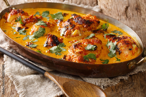 Kenyan Kuku Paka is a chicken roasted over charcoal and then cooked in a coconut curry closeup in the pan on the table. Horizontal