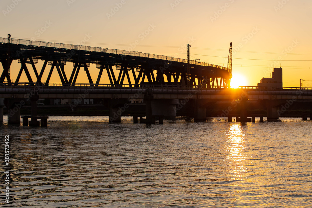 建築中の鉄橋と夕日と巨大な河川