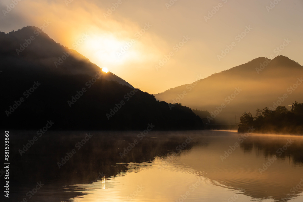 湖と山の稜線から昇る朝日