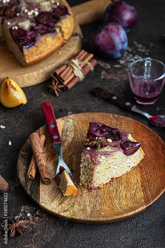 Homemade sweet plum pie or cake with nuts and spices on wooden board, dark brown stone background. Fruit pie. Rustic style. Selective focus.