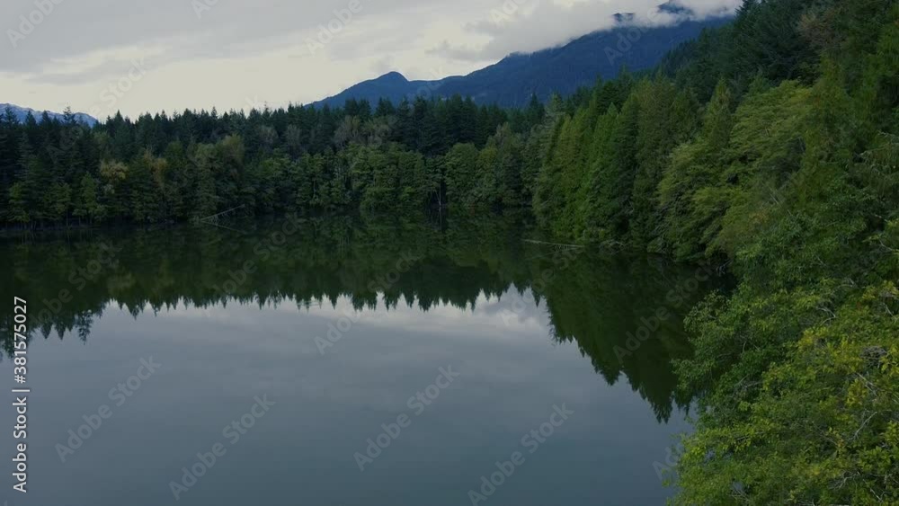 Mirror like lake with the reflection of green pine forest and mountains Mirror like lake with the reflection of green pine forest and mountains