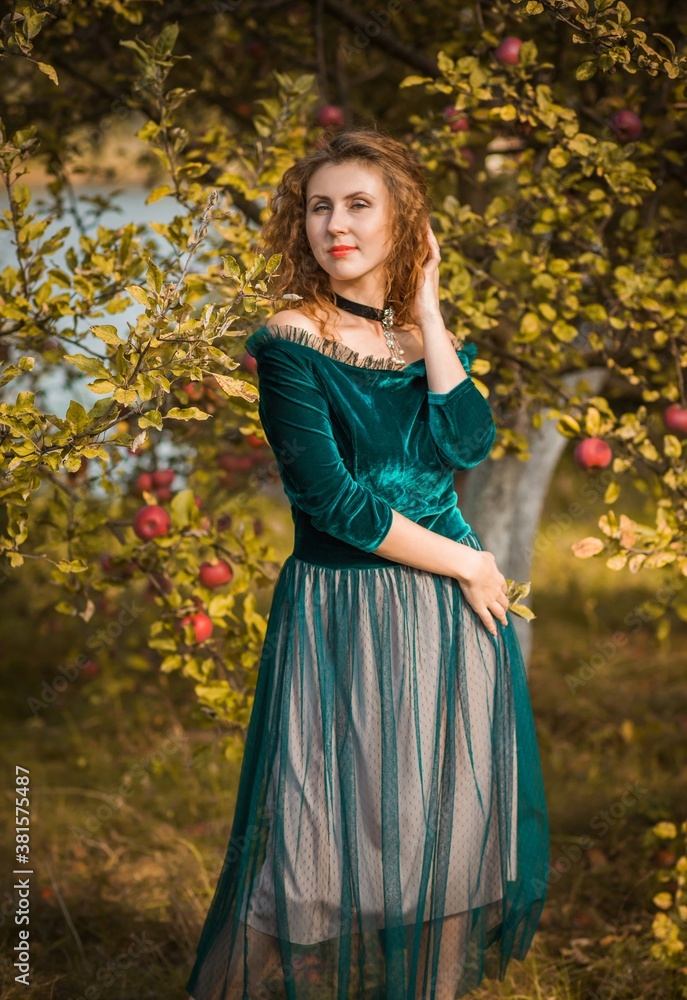 Woman in green velvet romantic dress, ladies pretty style, autumn nature at background Woman in green velvet romantic dress, ladies pretty style, autumn nature at background