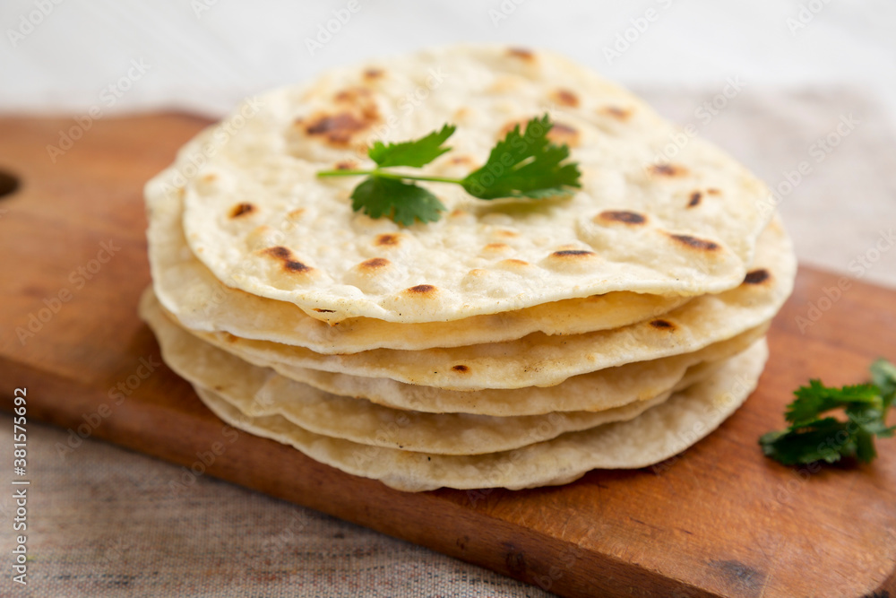 Homemade Roti Chapati Flatbread on a rustic wooden board, side view. Close-up.