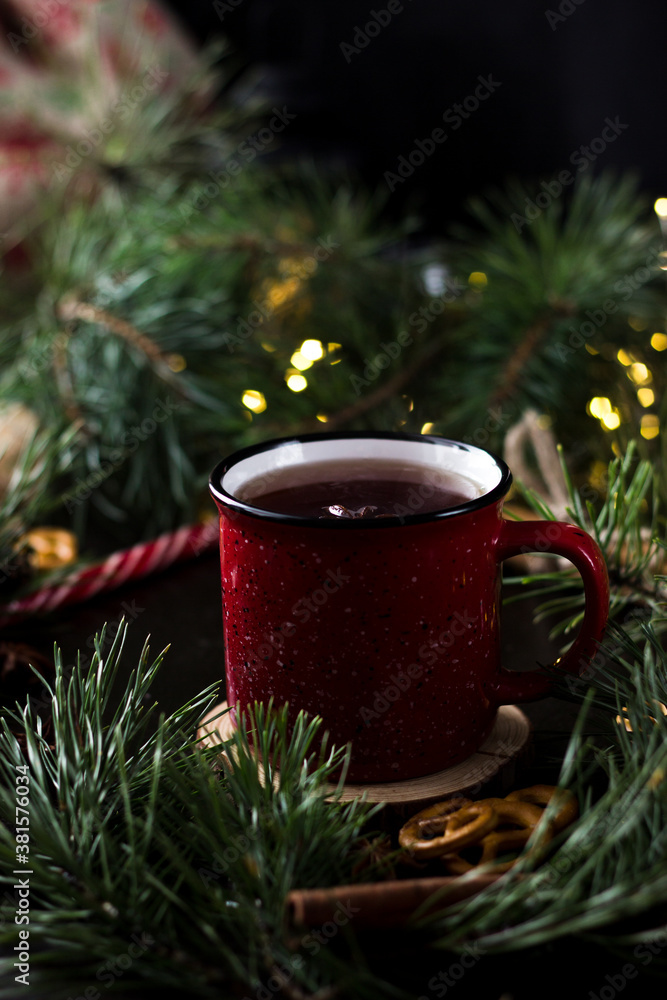 New year's tea party with spices. Red mug with tea surrounded by garlands, fir branches and spices
New year's tea party with spices. Red mug with tea surrounded by garlands, fir branches and spices
