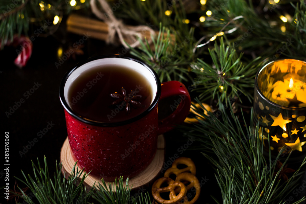 New year's tea party with spices. Red mug with tea surrounded by garlands, fir branches and spices
New year's tea party with spices. Red mug with tea surrounded by garlands, fir branches and spices