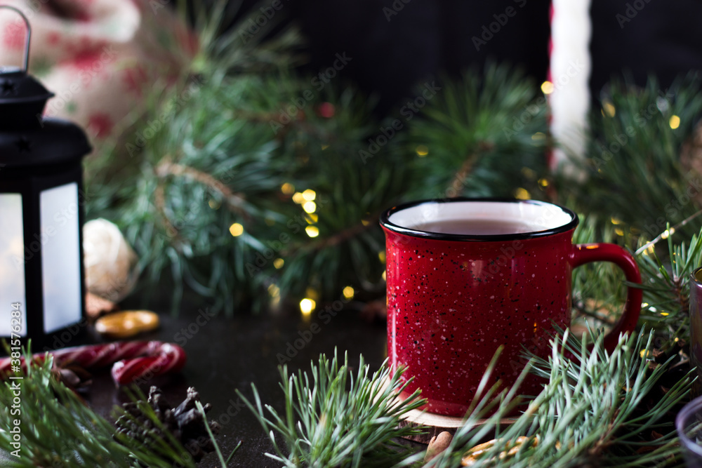 New year's tea party with spices. Red mug with tea surrounded by garlands, fir branches and spices
New year's tea party with spices. Red mug with tea surrounded by garlands, fir branches and spices